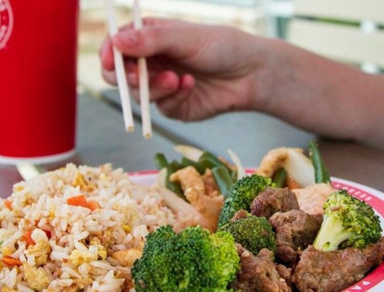 food on a plate and someone using chopsticks