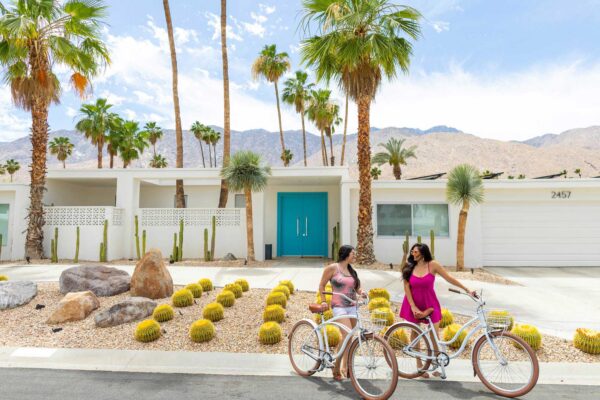 Two women on bikes in front of home