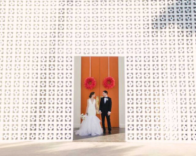 Newlyweds posing in front of iconic orange front doors at the Parker Palm Springs